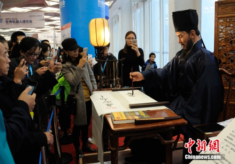 “王阳明”仿真机器人在世界机器人大会上秀书法。中新社发 玉龙 摄